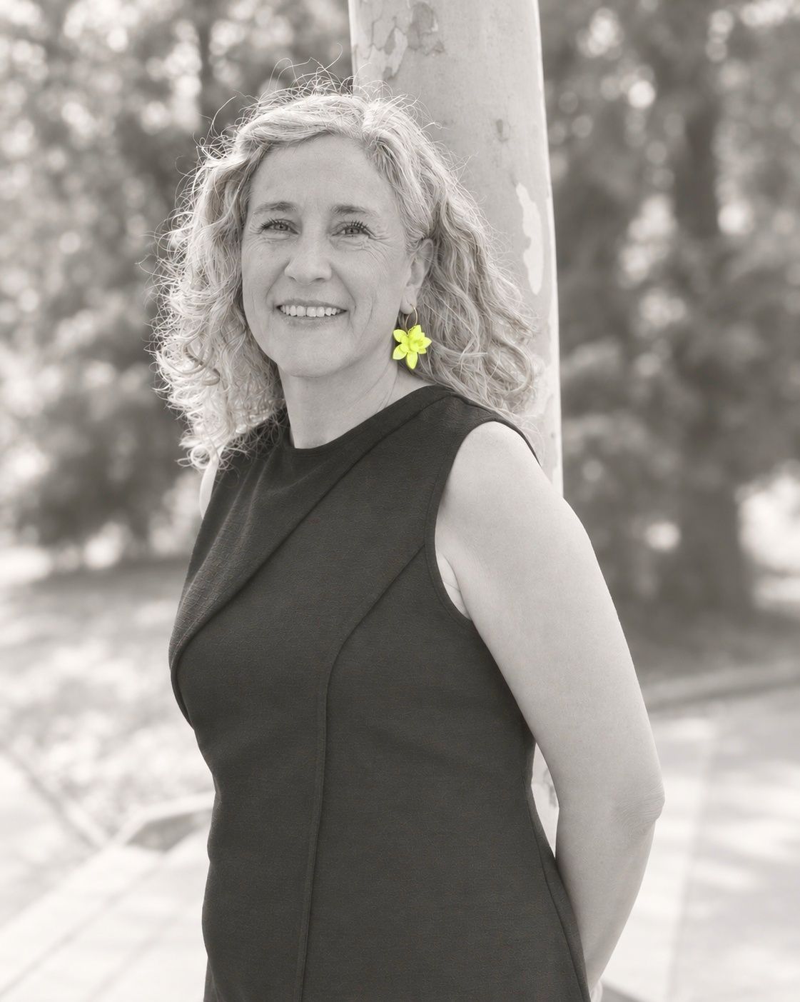 Pilar sonriendo en un parque, junto a un árbol